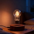 Glowing floating bulb above a round lamp base on a desk